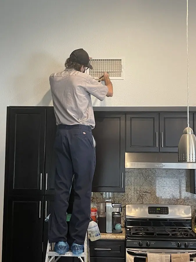 Technician inspecting an air vent during HVAC service in Conyers